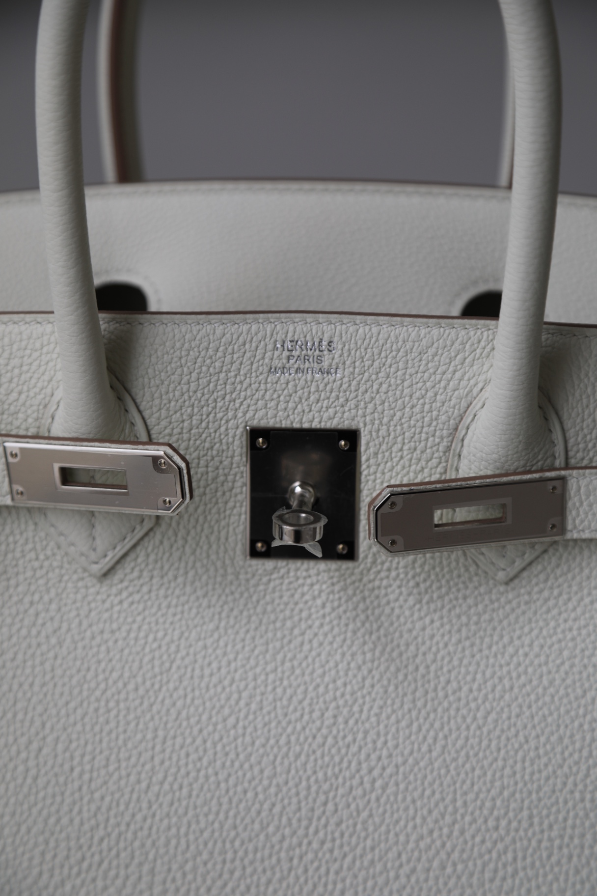Palladium hardware and Hermès Paris hallmark on white togo leather